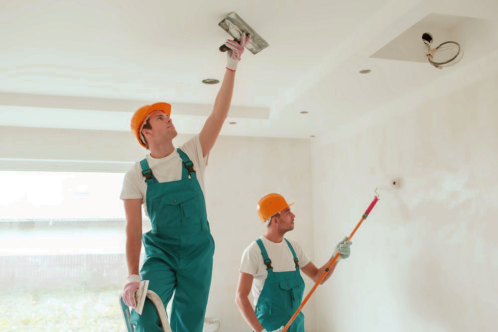 Two gentlement with orange painting a white room